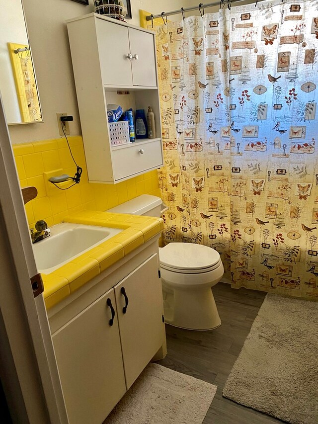 bathroom with a shower with shower curtain, wood-type flooring, vanity, and toilet