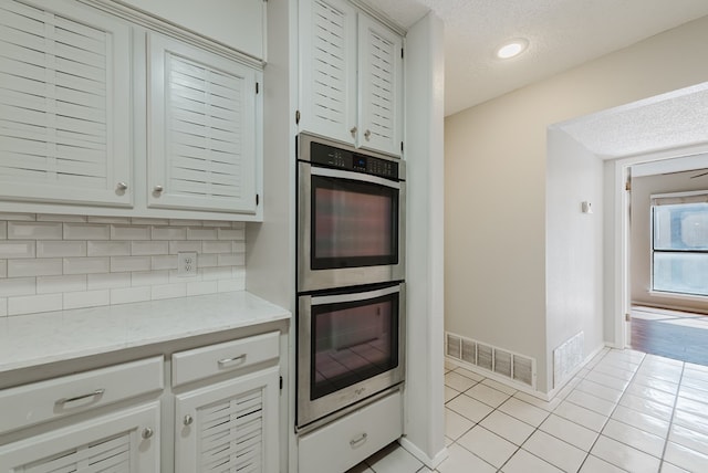 4106 Dyer Cir, Midland, TX 79707 - kitchen with backsplash, stainless steel double oven, a textured ceiling, visible vents, and light tile patterned flooring