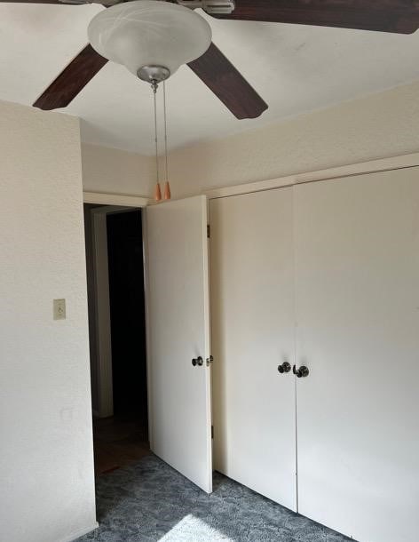 unfurnished bedroom featuring dark carpet and ceiling fan