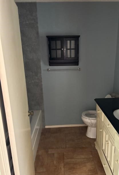 bathroom featuring a tub to relax in, vanity, and toilet