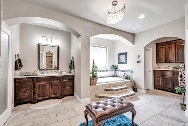 bathroom with a garden tub, baseboards, visible vents, and two vanities
