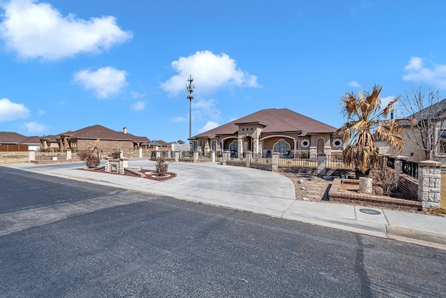 view of front of home featuring a fenced front yard, a residential view, and concrete driveway