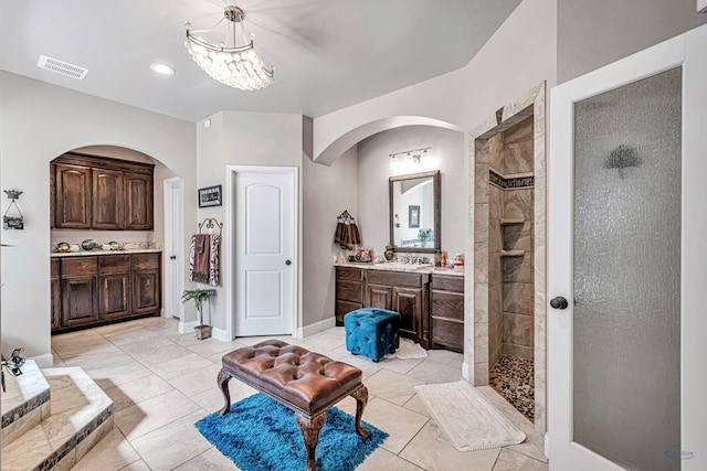 bathroom with baseboards, visible vents, an inviting chandelier, walk in shower, and vanity