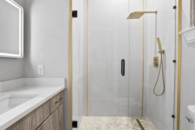 bathroom featuring a shower with door, vanity, and toilet