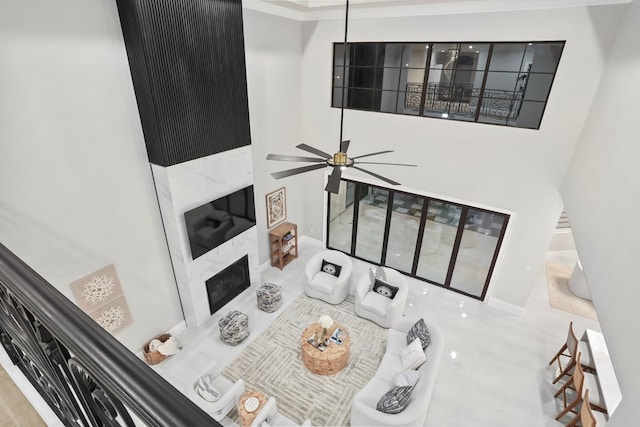 living room with a premium fireplace, ceiling fan, and ornamental molding