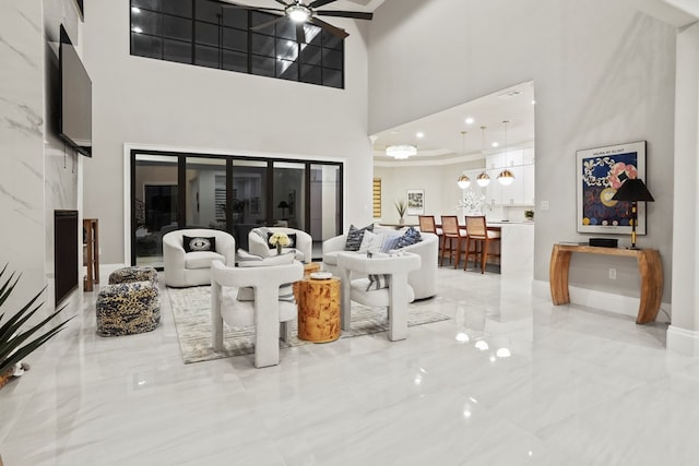 living room with ceiling fan and a high ceiling