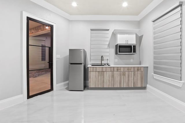 kitchen with white cabinets, appliances with stainless steel finishes, crown molding, and sink