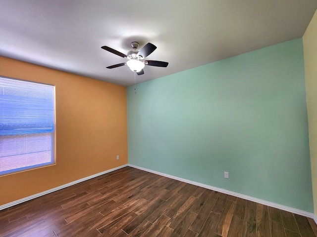 unfurnished room with dark wood-type flooring, a ceiling fan, and baseboards