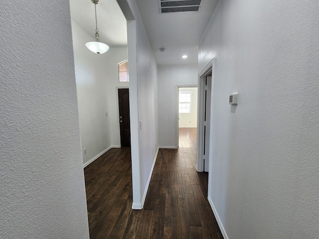 hall with baseboards, visible vents, dark wood-style flooring, and arched walkways