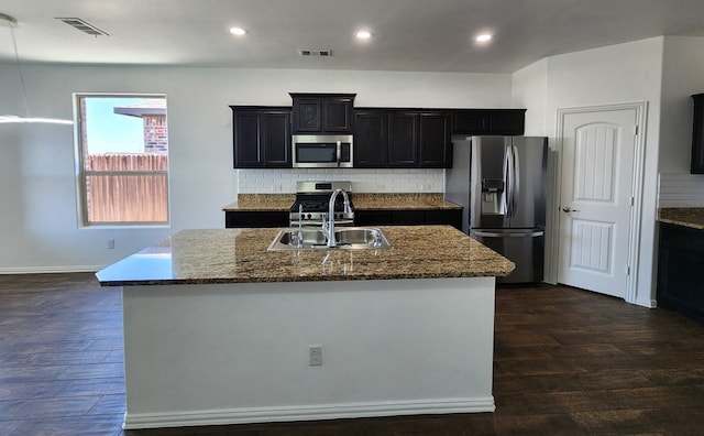 kitchen with dark stone countertops, visible vents, dark wood finished floors, a sink, and appliances with stainless steel finishes