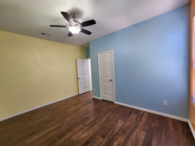 empty room featuring visible vents, dark wood-style floors, baseboards, and ceiling fan