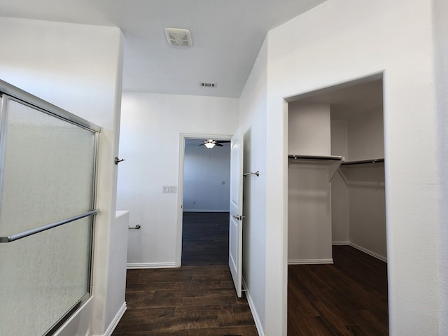 interior space with a shower with door, visible vents, a walk in closet, wood finished floors, and a ceiling fan