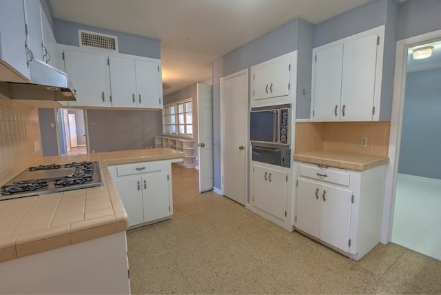 kitchen with stainless steel gas stovetop, tile countertops, and white cabinets