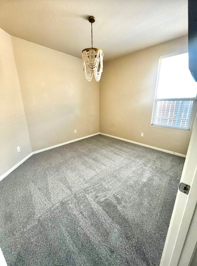 unfurnished room with carpet flooring, a chandelier, baseboards, and a textured ceiling