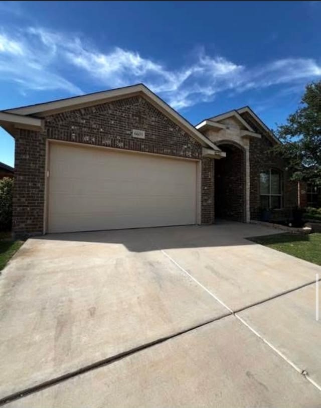 ranch-style home featuring brick siding, an attached garage, and driveway