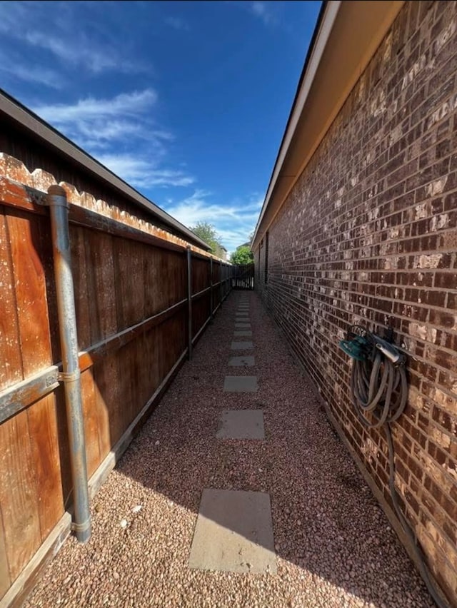 view of side of home featuring fence and brick siding