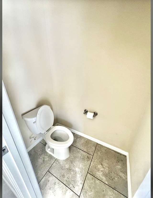 bathroom featuring tile patterned flooring, toilet, and baseboards