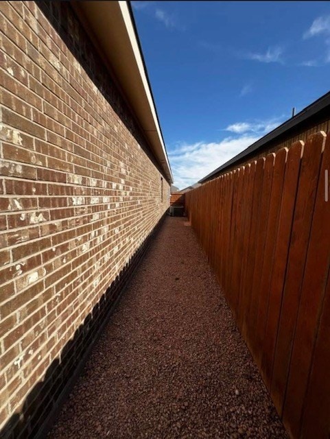 view of home's exterior featuring brick siding and fence