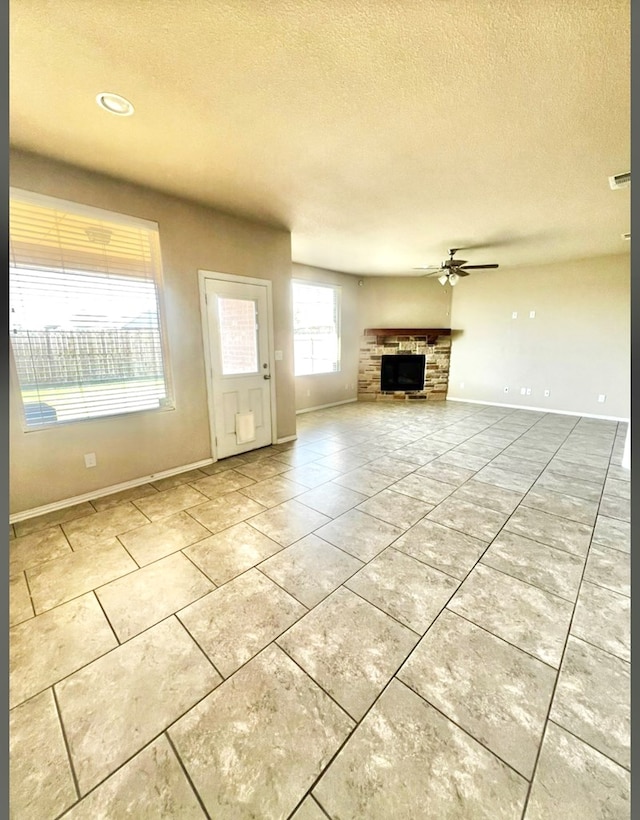 6609 Colony Rd, Midland, TX 79706 - unfurnished living room with a textured ceiling, a fireplace, ceiling fan, and tile patterned floors
