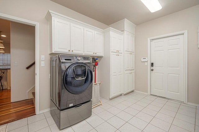 washroom featuring light tile patterned floors, cabinet space, washer / dryer, and baseboards