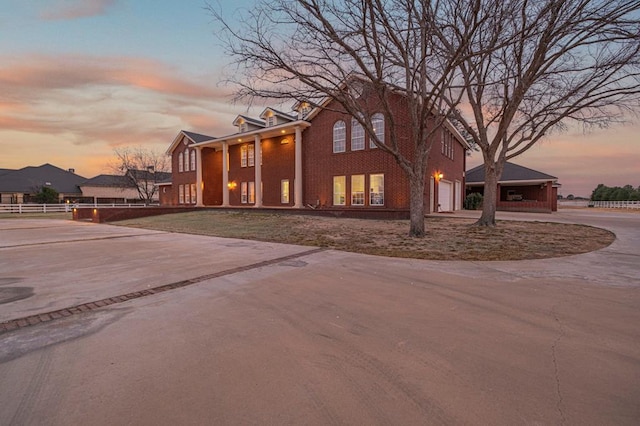 view of front facade with a garage, driveway, and fence