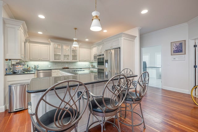 kitchen featuring wood finished floors, appliances with stainless steel finishes, backsplash, and crown molding