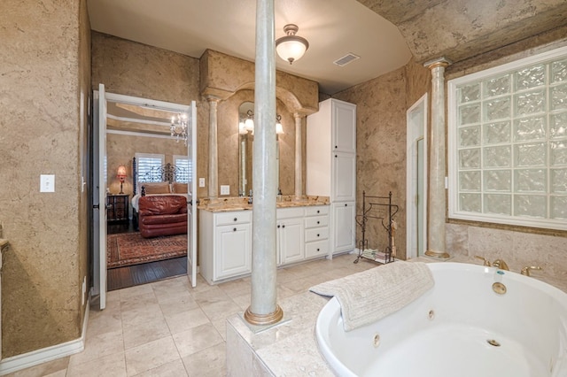 bathroom with connected bathroom, visible vents, vanity, a jetted tub, and ornate columns