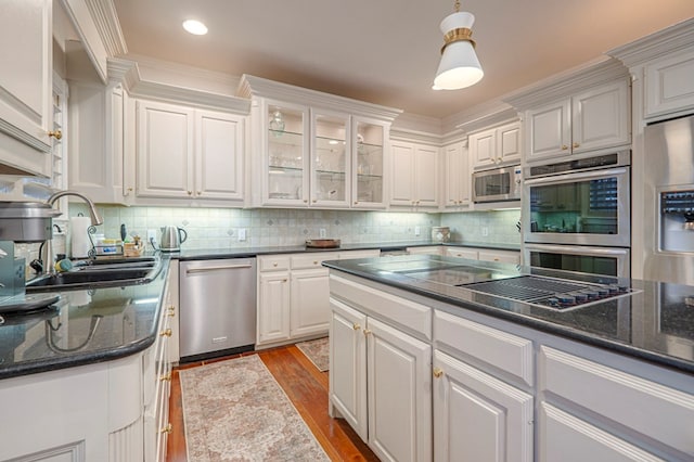 kitchen with stainless steel appliances, white cabinets, a sink, and wood finished floors