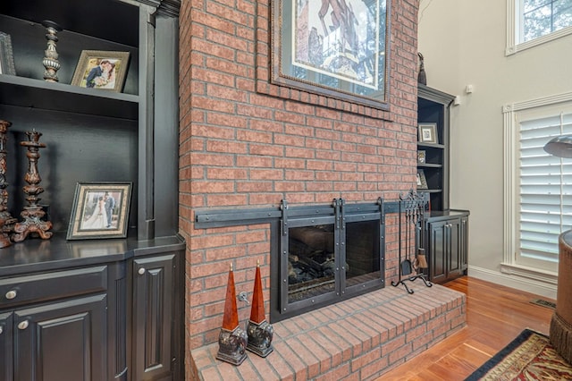 living room featuring a fireplace, baseboards, and wood finished floors