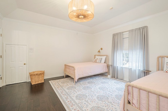 bedroom with crown molding, a tray ceiling, and dark wood-style flooring