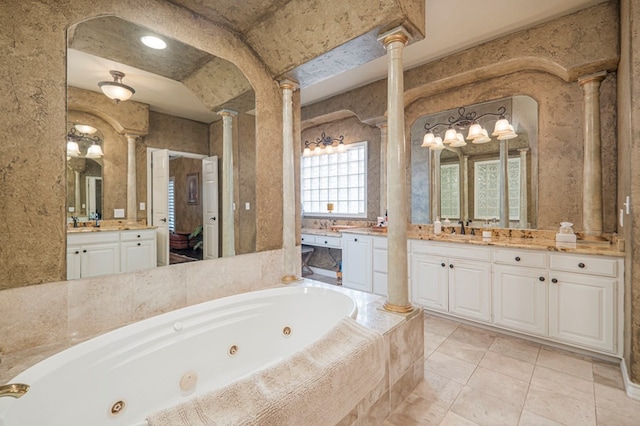 bathroom with decorative columns, two vanities, a sink, tile patterned flooring, and a jetted tub