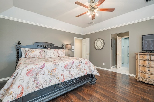 bedroom featuring a raised ceiling, visible vents, baseboards, and wood finished floors