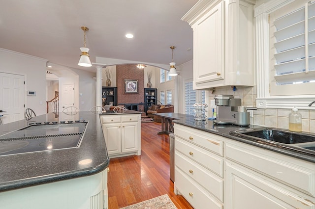 kitchen with arched walkways, crown molding, dark countertops, and black electric cooktop