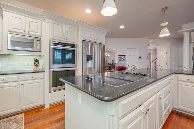 kitchen with white cabinets, decorative backsplash, appliances with stainless steel finishes, decorative light fixtures, and light wood-type flooring