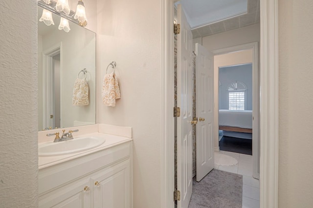 bathroom featuring a textured wall, tile patterned flooring, connected bathroom, and vanity