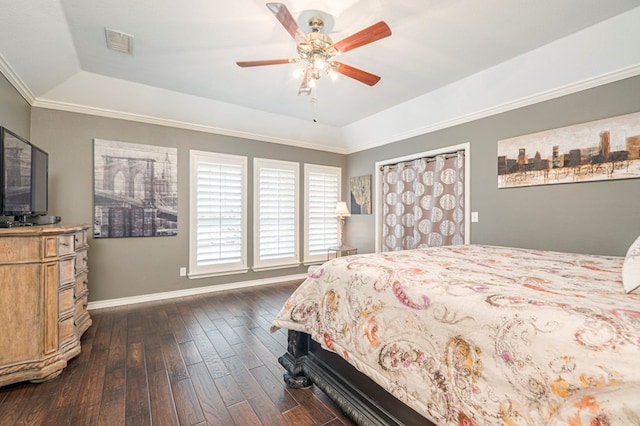 bedroom with baseboards, visible vents, a raised ceiling, dark wood finished floors, and crown molding