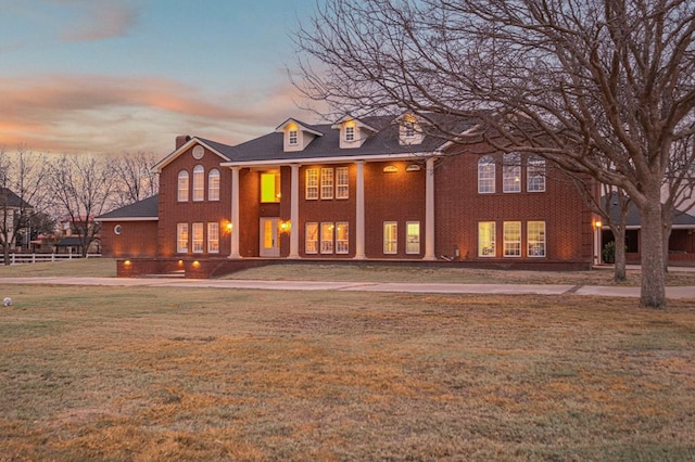 rear view of property with brick siding and a lawn