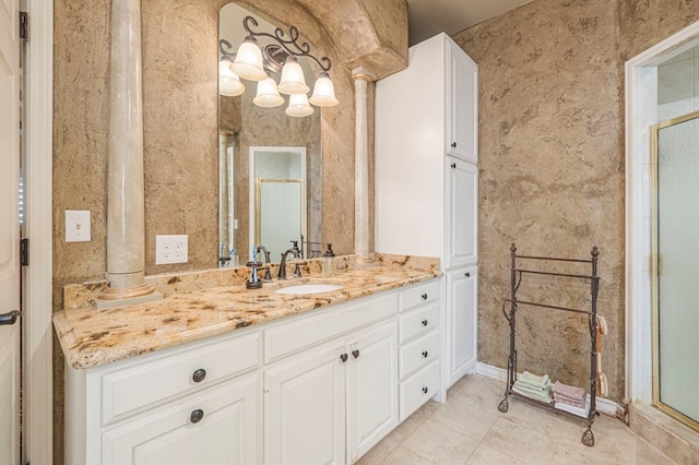 bathroom with a shower with door, decorative columns, wallpapered walls, vanity, and tile patterned floors