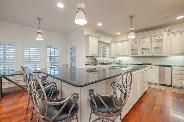 kitchen with ornamental molding, backsplash, wood finished floors, and a center island