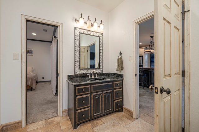 bathroom featuring connected bathroom, visible vents, vanity, baseboards, and stone tile flooring