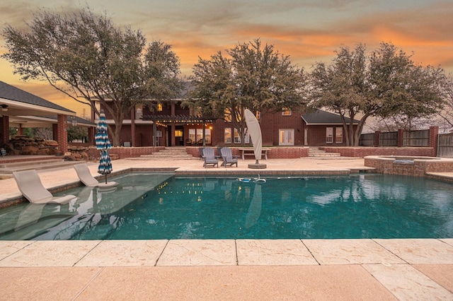 view of swimming pool featuring a pool with connected hot tub, fence, and a patio