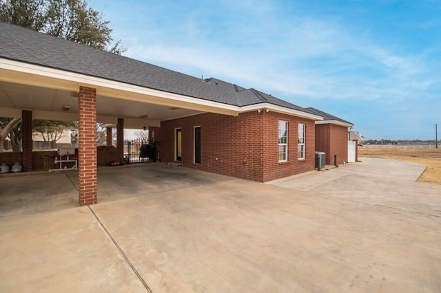 view of side of home featuring an attached carport, brick siding, driveway, and central AC unit