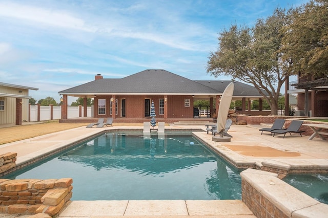 view of swimming pool with a patio area, fence, and a pool with connected hot tub