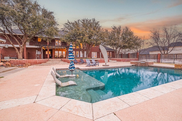 view of pool featuring a patio area, fence, and a pool with connected hot tub