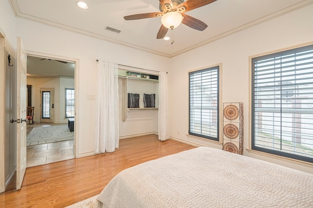 bedroom with light wood-style floors, multiple windows, visible vents, and crown molding