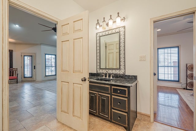 bathroom featuring ceiling fan, ornamental molding, vanity, and baseboards