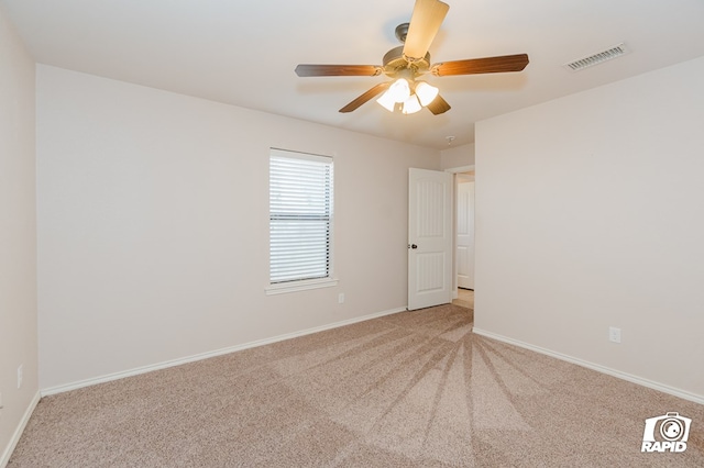 empty room featuring visible vents, carpet floors, baseboards, and ceiling fan