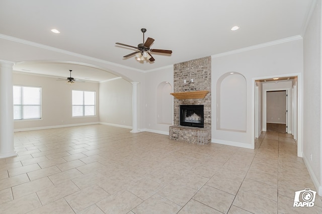 unfurnished living room featuring crown molding, a brick fireplace, decorative columns, and ceiling fan