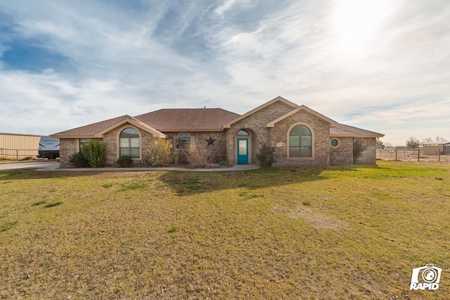 ranch-style home featuring a front yard, brick siding, and roof with shingles