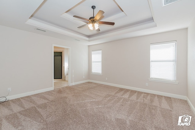 empty room with a ceiling fan, baseboards, visible vents, light carpet, and a raised ceiling